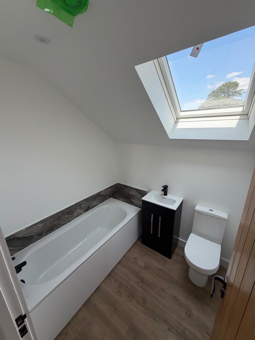 Loft bathroom installation with bath, vanity basin and skylight
