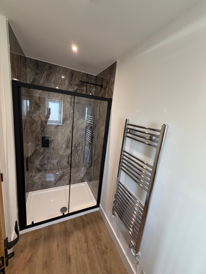 Sliding-door shower with marble-effect panels and chrome towel radiator